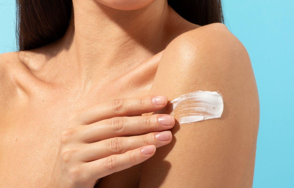 Young woman applying body creme