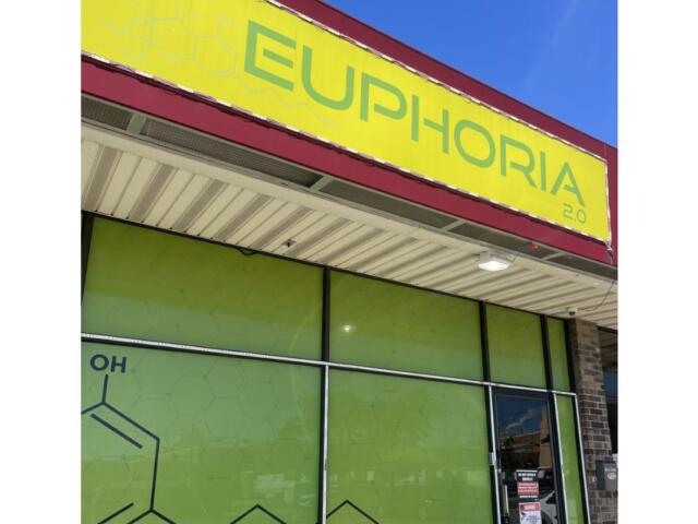 Exterior storefront with a bright yellow sign reading 'EUPHORIA 2.0' above lime-green glass windows and a doorway to the right.