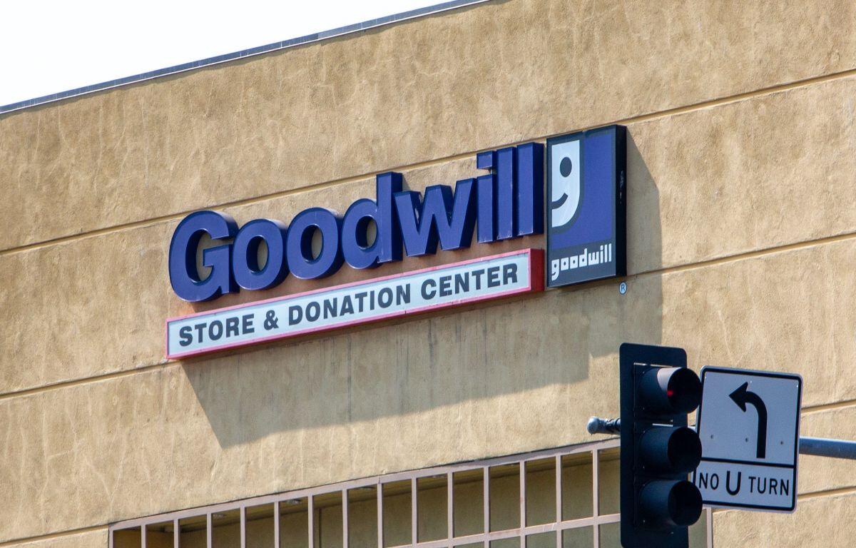 Goodwill Store & Donation Center sign on a beige wall with the blue goodwill logo to the right and a traffic light in the foreground.