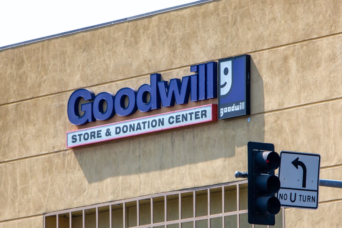 Goodwill Store & Donation Center sign on a beige wall with the blue goodwill logo to the right and a traffic light in the foreground.