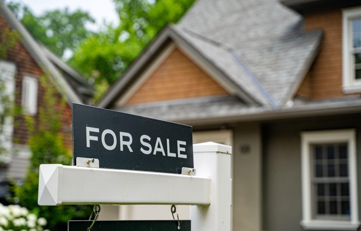 For sale sign in front yard of a suburban house.