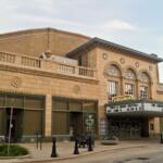 Historic theater with a curved marquee reading 'Virginia' on a beige brick facade, empty street beneath it.