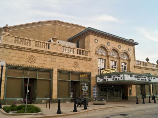 Historic theater with a curved marquee reading 'Virginia' on a beige brick facade, empty street beneath it.