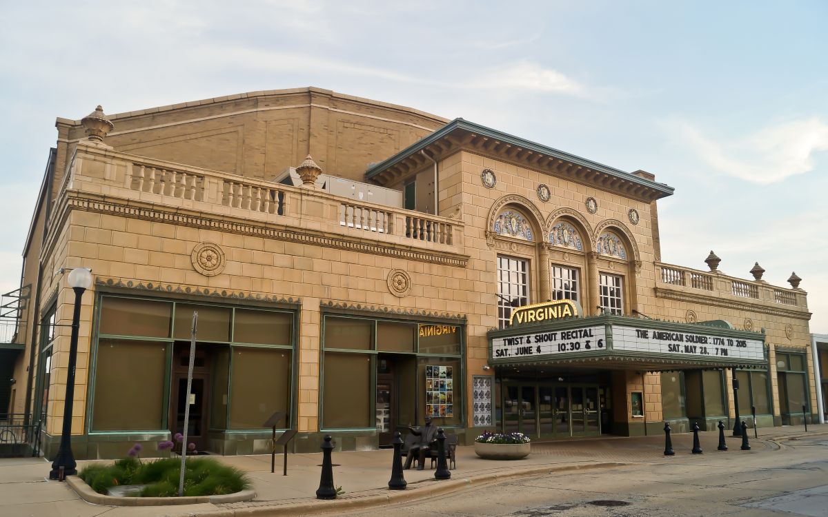 Historic theater with a curved marquee reading 'Virginia' on a beige brick facade, empty street beneath it.