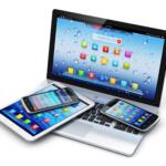 Angled group of tablets and smartphones resting on a laptop keyboard, screens filled with colorful app icons.