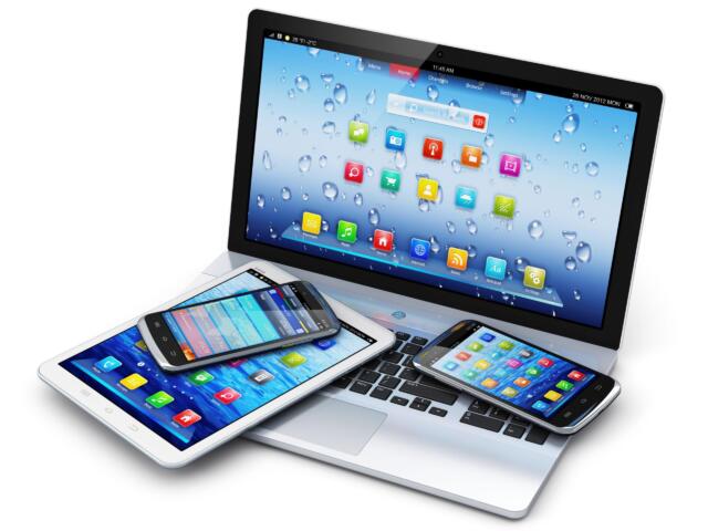 Angled group of tablets and smartphones resting on a laptop keyboard, screens filled with colorful app icons.