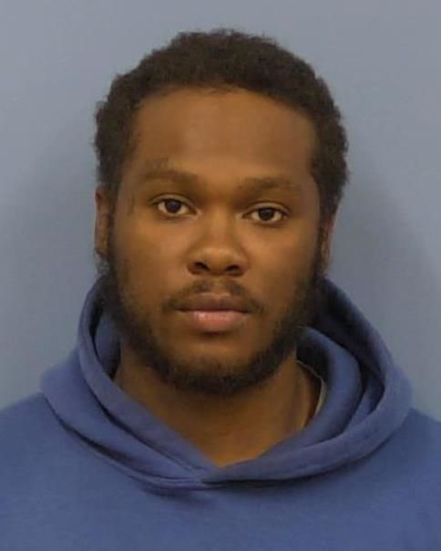 Portrait of a man with short hair and beard wearing a blue hoodie against a gray background.