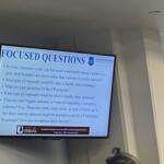 Presentation slide reading 'FOCUSED QUESTIONS' with bulleted items and a City of Urbana logo at the bottom left in a conference room setting.