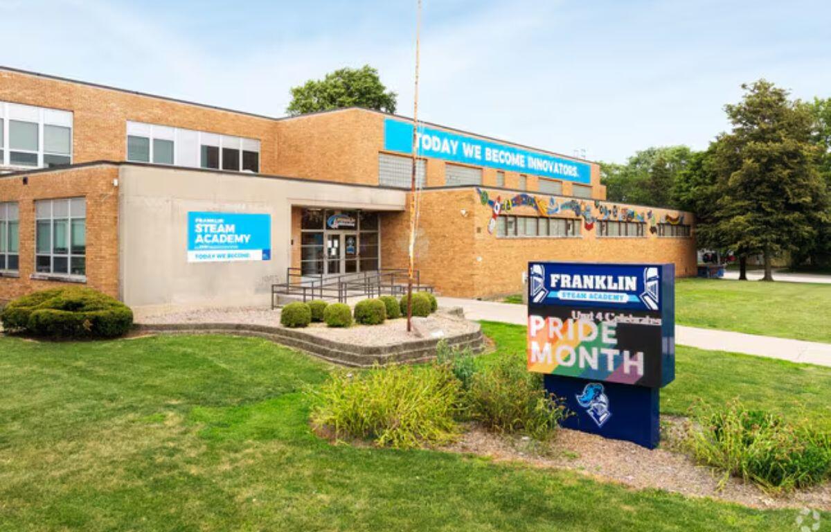 Exterior view of Franklin STEAM Academy, a brick school building with Pride Month signage in the front yard display.