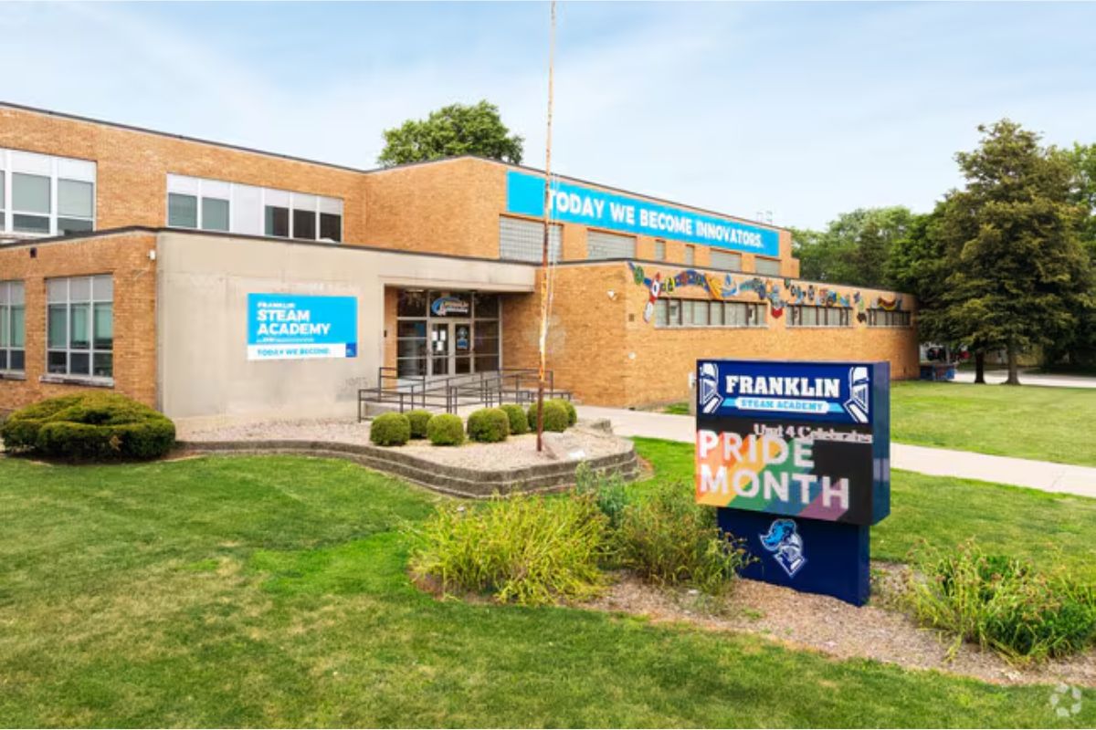 Exterior view of Franklin STEAM Academy, a brick school building with Pride Month signage in the front yard display.