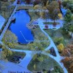 Aerial view of a park with a kidney-shaped basin labeled 'Basin Excavation' and a raised 'Retaining Wall' along the water, surrounded by trees and pathways.