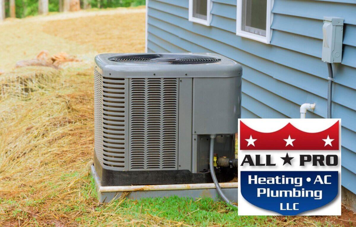 Outdoor air conditioner condenser unit beside a blue house, with an All Pro Heating AC Plumbing LLC logo overlay in the corner.