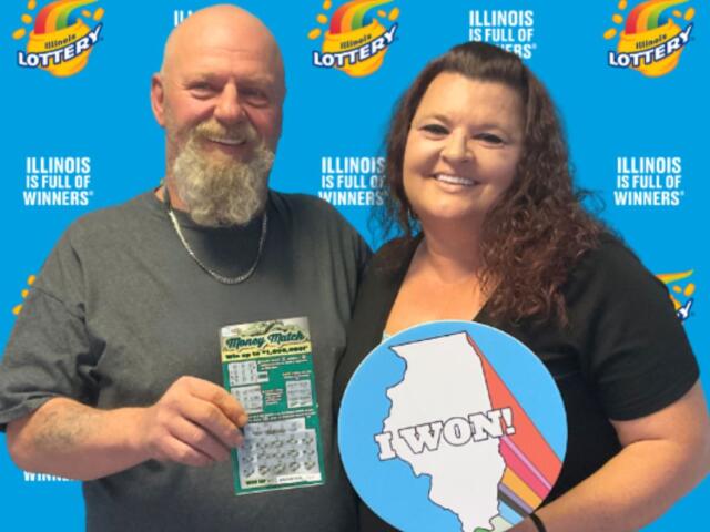 Two smiling adults pose in front of an Illinois Lottery backdrop; man holds a scratch-off ticket, woman holds a round 'I WON!' sign with the Illinois silhouette and colorful stripes.