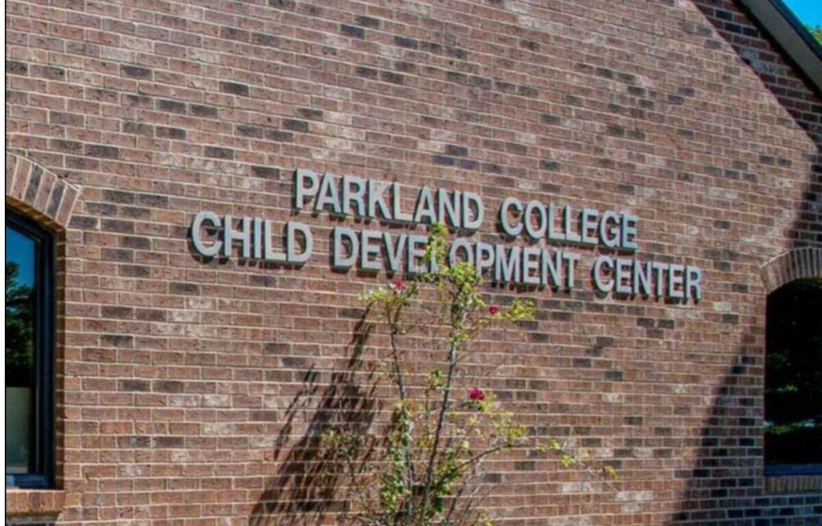 Brick wall with the sign 'Parkland College Child Development Center' on a brick building, with a small flowering shrub in front.