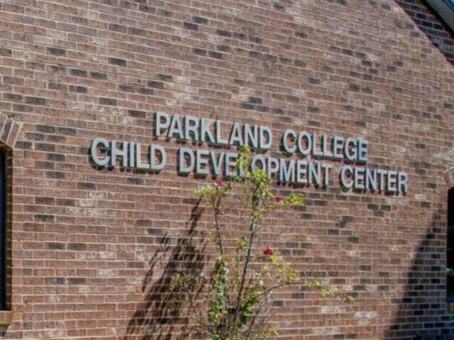 Brick wall with the sign 'Parkland College Child Development Center' on a brick building, with a small flowering shrub in front.