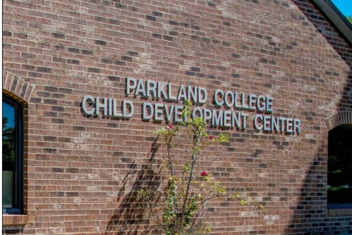 Brick wall with the sign 'Parkland College Child Development Center' on a brick building, with a small flowering shrub in front.