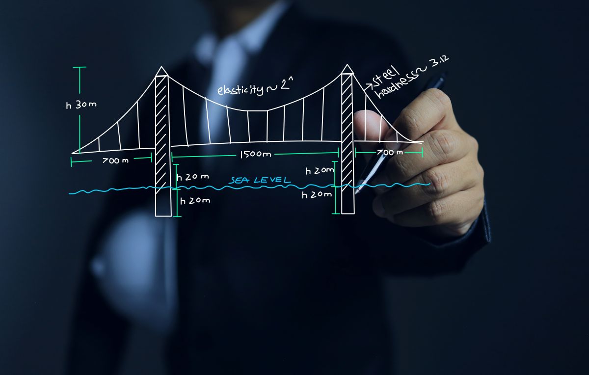 Person in a suit draws a suspension-bridge sketch with measurements (700 m, 1500 m) and sea level line on a transparent board/textbook-style diagram