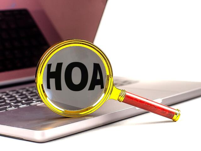 Magnifying glass with the word HOAX on a laptop keyboard, symbolizing debunking misinformation online.