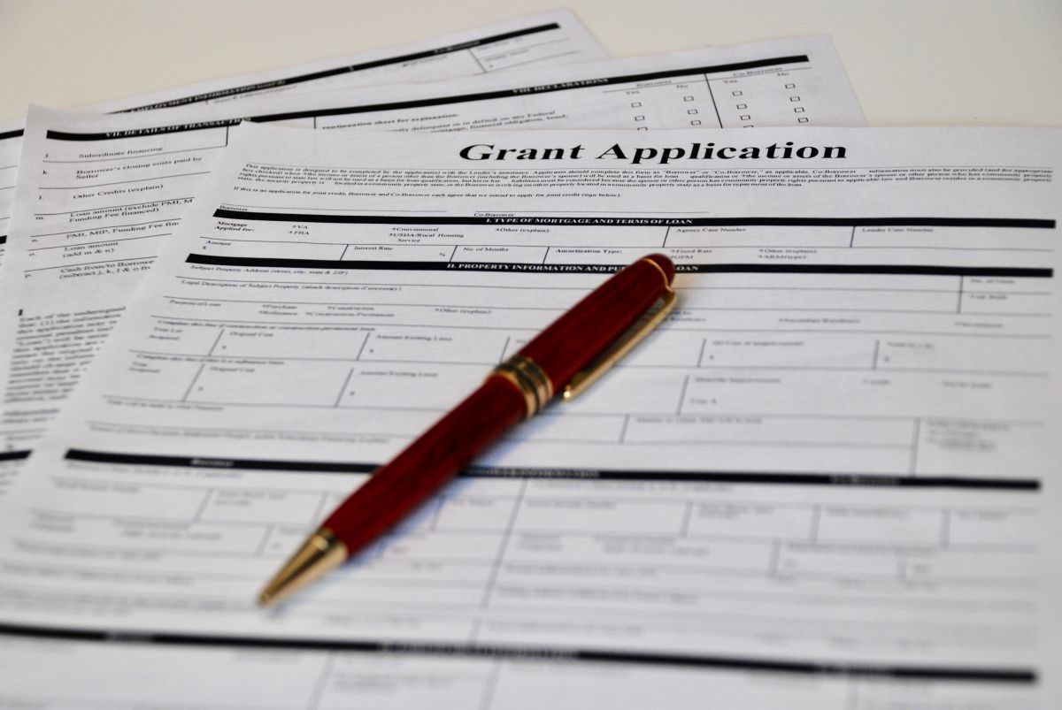 Grant application form with a red fountain pen resting on top on a white table.