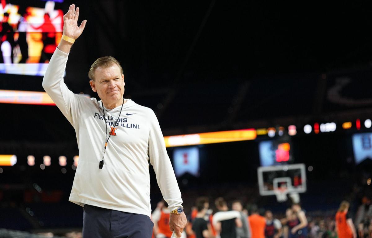 Illinois Fighting Illini coach waves to the crowd on a basketball court.