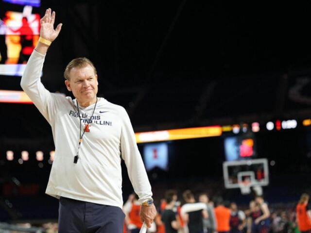 Illinois Fighting Illini coach waves to the crowd on a basketball court.