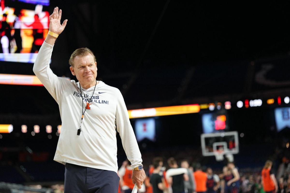 Illinois Fighting Illini coach waves to the crowd on a basketball court.
