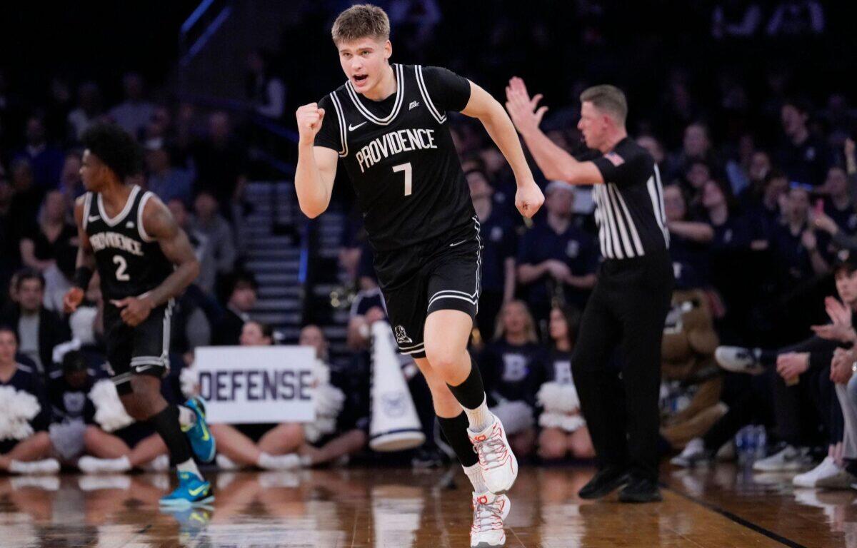 Providence basketball player in black jersey (number 1) sprinting on the court during a game, with defender and referee in background.