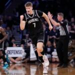 Providence basketball player in black jersey (number 1) sprinting on the court during a game, with defender and referee in background.