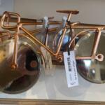 Copper bicycle-shaped pizza cutter with two large circular blades as wheels and a price tag attached