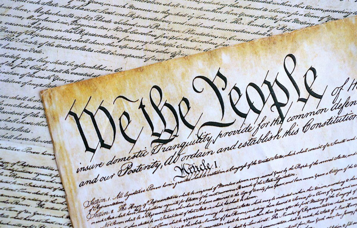 The U.S. Constitution scroll with the words 'We the People' in calligraphic script, part of a historical document display.