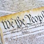 The U.S. Constitution scroll with the words 'We the People' in calligraphic script, part of a historical document display.