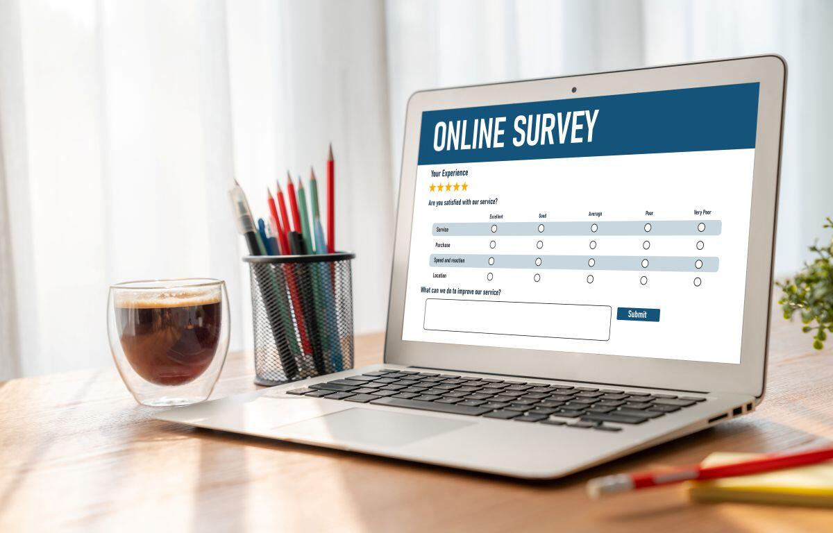 Laptop on a wooden desk showing an online survey form on screen, with star ratings and a text box for feedback