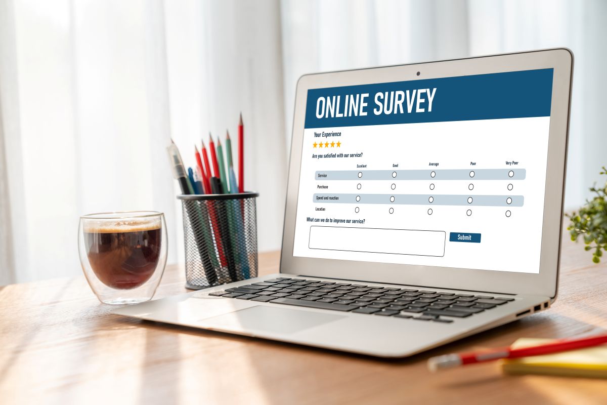 Laptop on a wooden desk showing an online survey form on screen, with star ratings and a text box for feedback