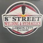 Circular sign for 8th Street Welding & Hydraulics in Gibson City, Illinois, with a welding torch graphic in the center.